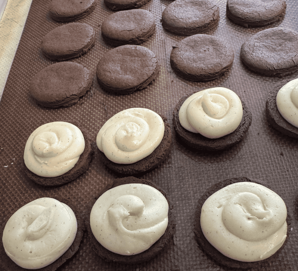 4 of brown circle cookies and white creme on top of the cookies in the last 2 rows