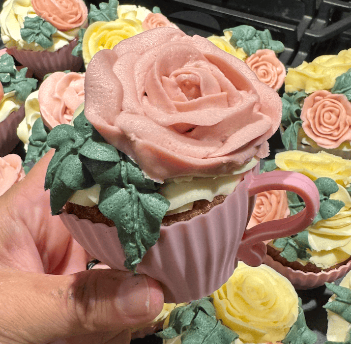 A sea of beautifully piped buttercream rose petal flowers and designs on vanilla cupcakes that are baked into silicone pink tea cups.