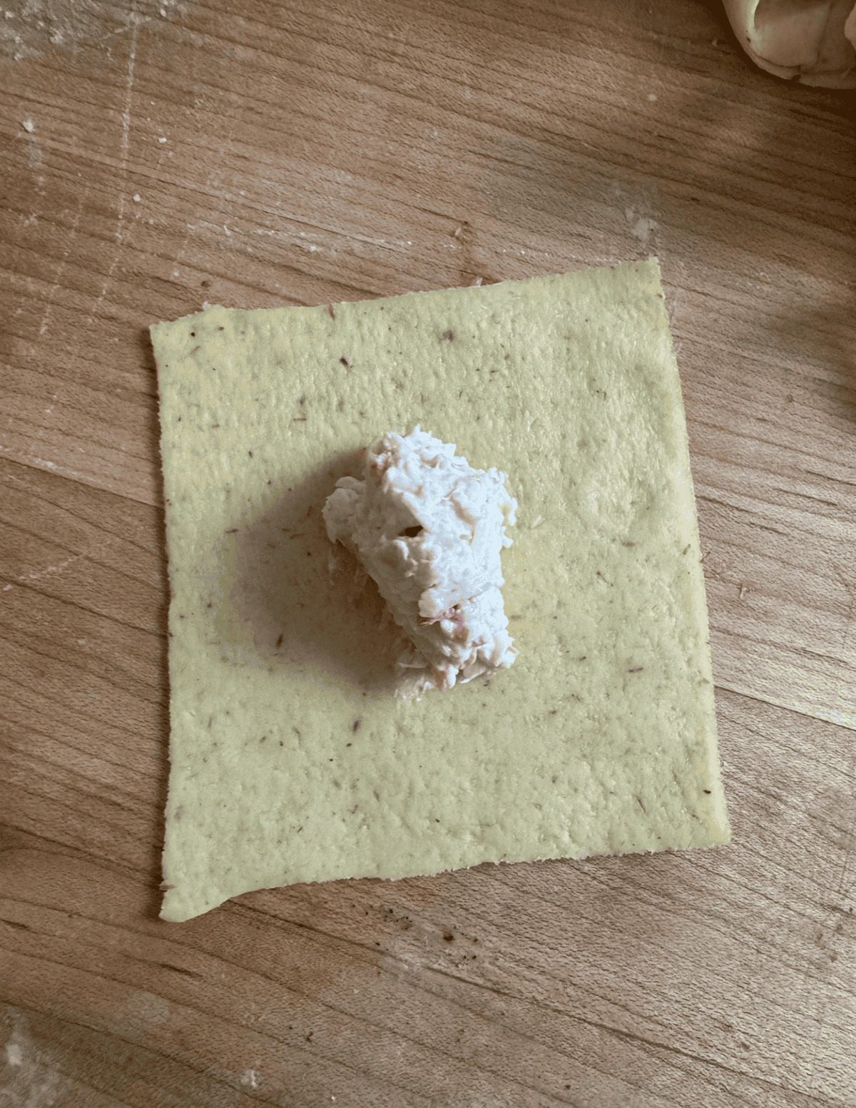 square wonton wrapper with gluten free crab rangoon filling in the middle.