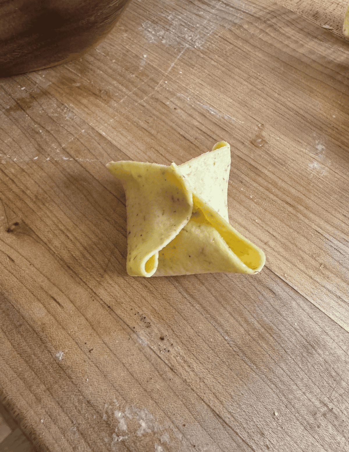 Second step in forming crab rangoon by combining the remaining two opposite sides.