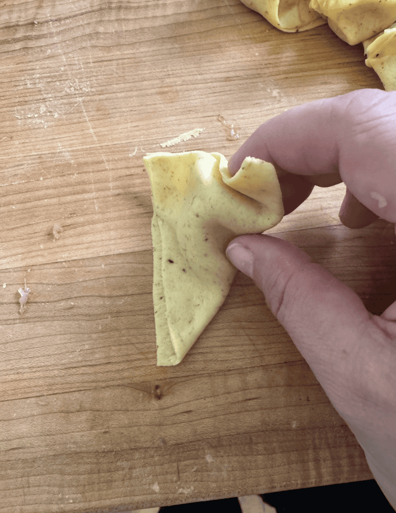Fried Wonton Shaping Step 5 fold the dough edges over on the indentation from the last step.