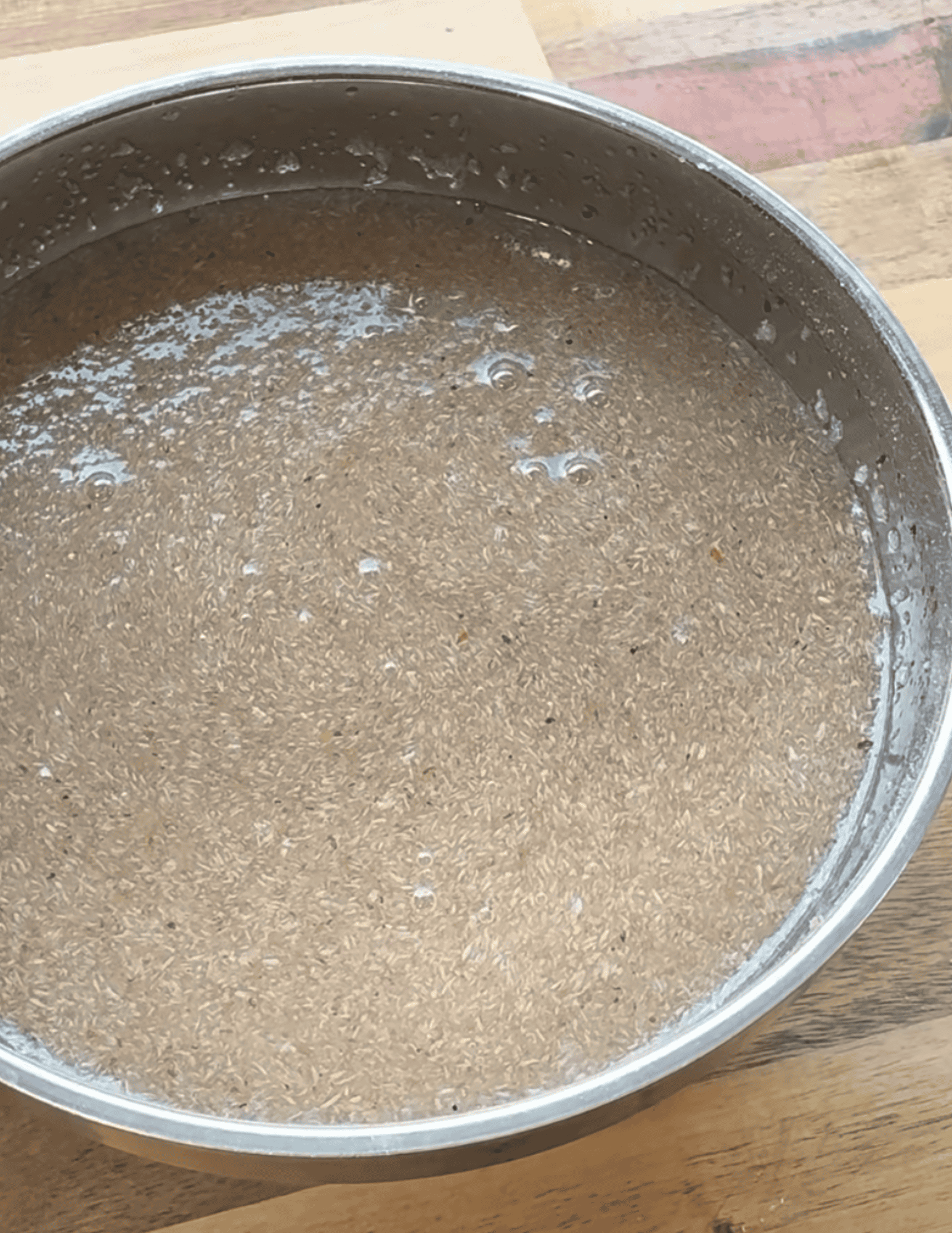 Soft, fluffy gluten-free pizza dough rising in a metal bowl on a wooden surface.