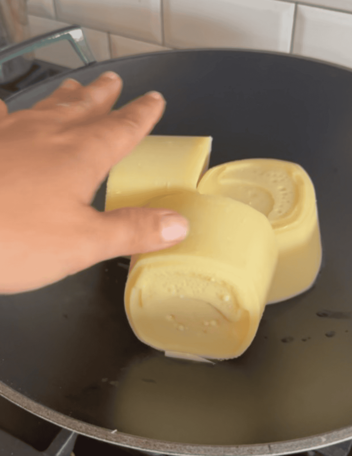 Three chunks of tallow heating up in a wok to prepare for frying.