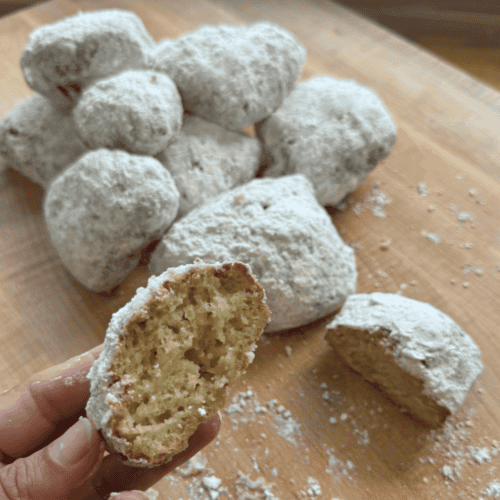 gluten free beignets with a bite taken out of them to show teh pillowy soft inside.