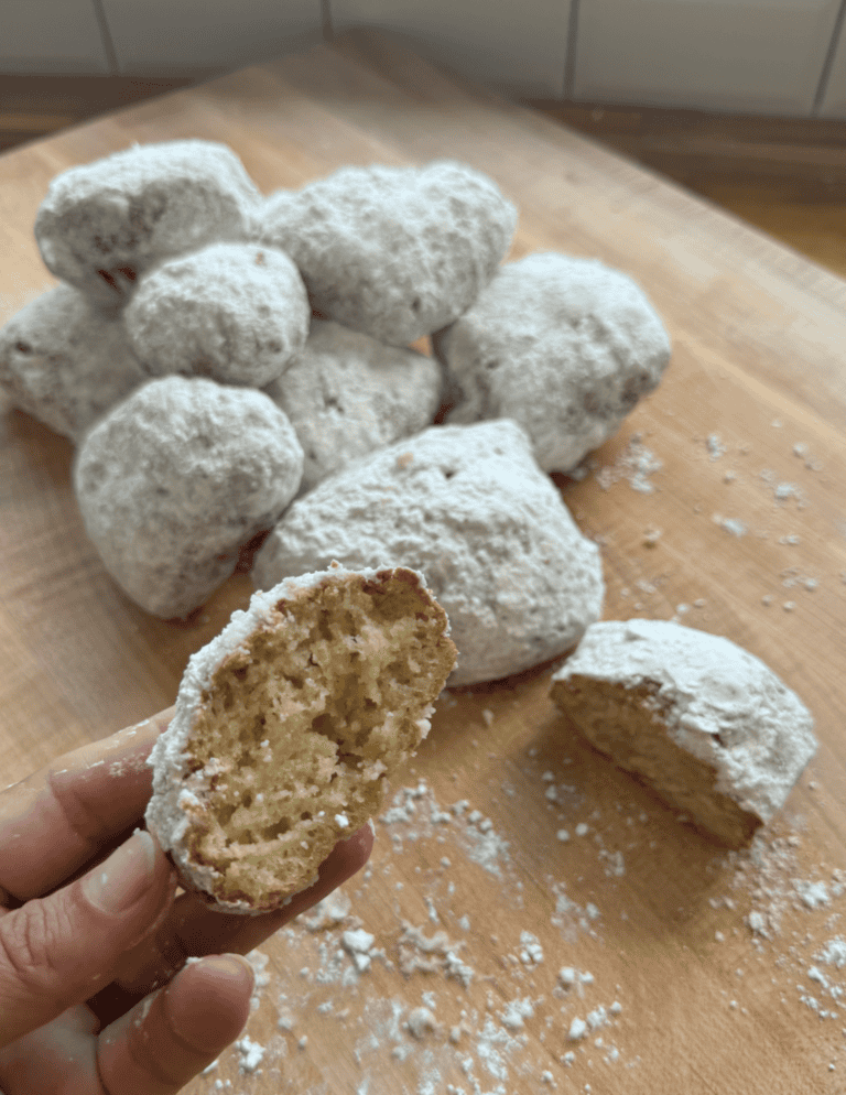 gluten free beignets with a bite taken out of them to show teh pillowy soft inside.