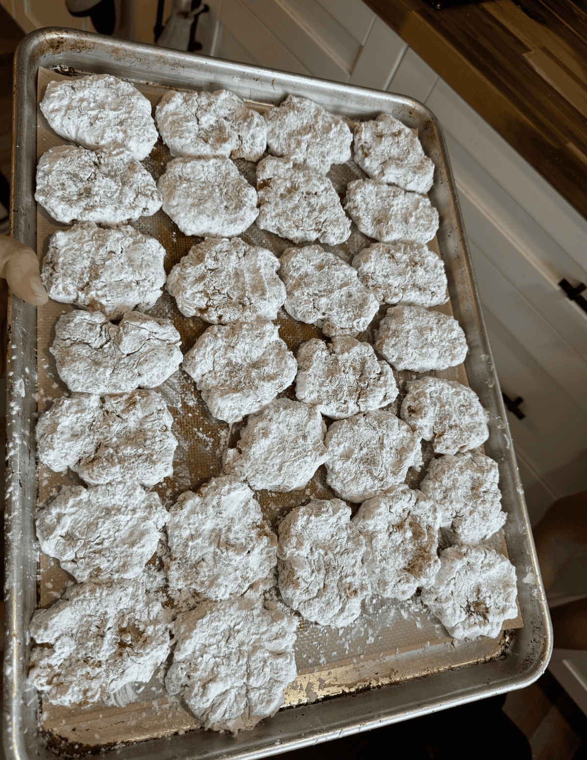 gluten free chicken nuggets covered in white arrowroot powder on a silicone lined cookie tray.