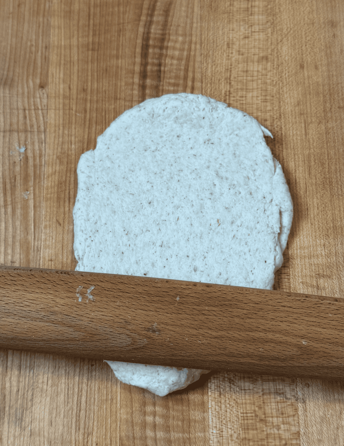 gluten free dumpling dough being rolled out with a wooden roller