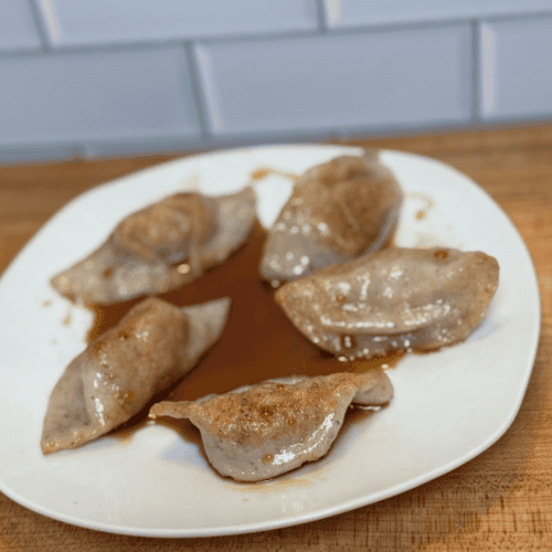 gluten free dumplings on a white plate with sauce on top.