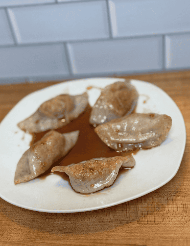 gluten free dumplings on a white plate with sauce on top.