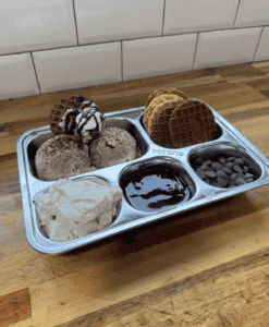 Gluten Free Ice Cream Nachos in a stainless steel separated bowl. Fillings include gluten free Pizelle Cookie, chocolate sauce, vanilla and chocolate ice cream, whipped cream and chocolate chips.