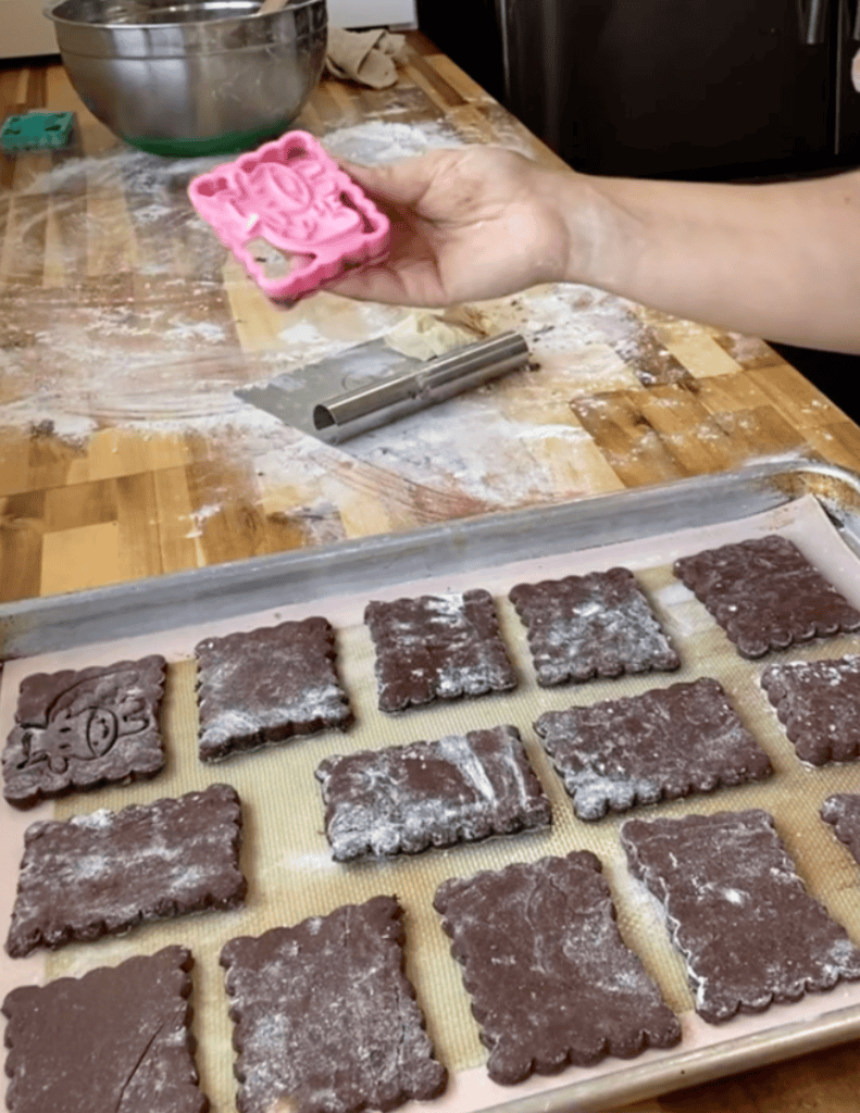 gluten free ice cream sandwich shells being cut out with a cookie cutter.