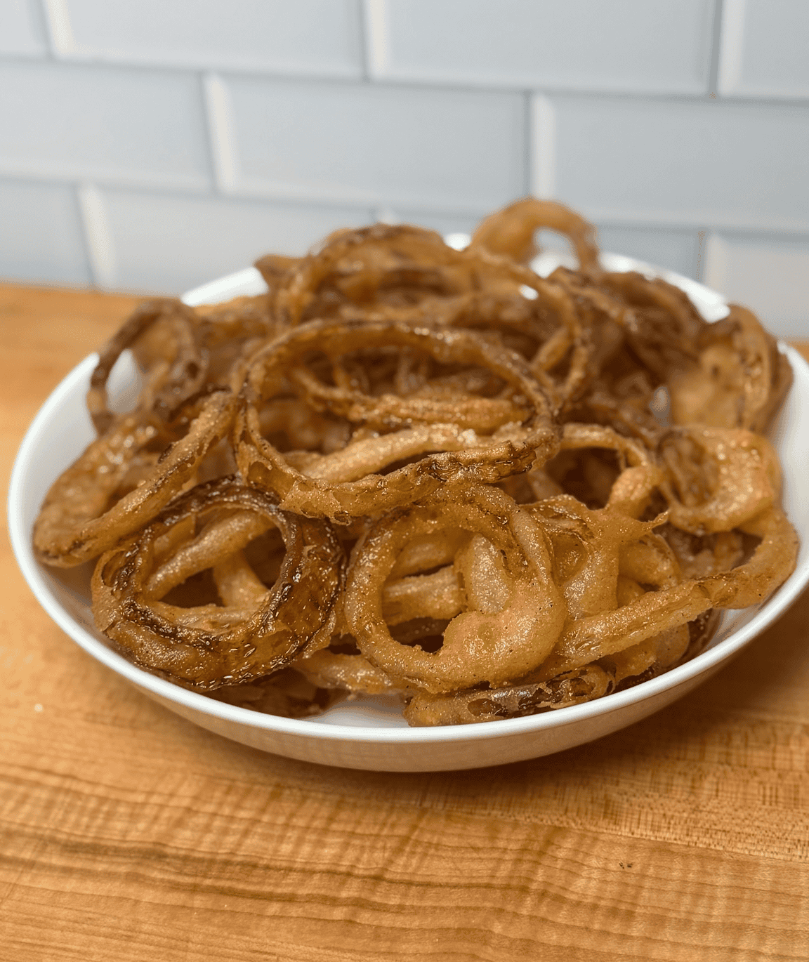 gluten free fried onion rings in a white bowl on the counter