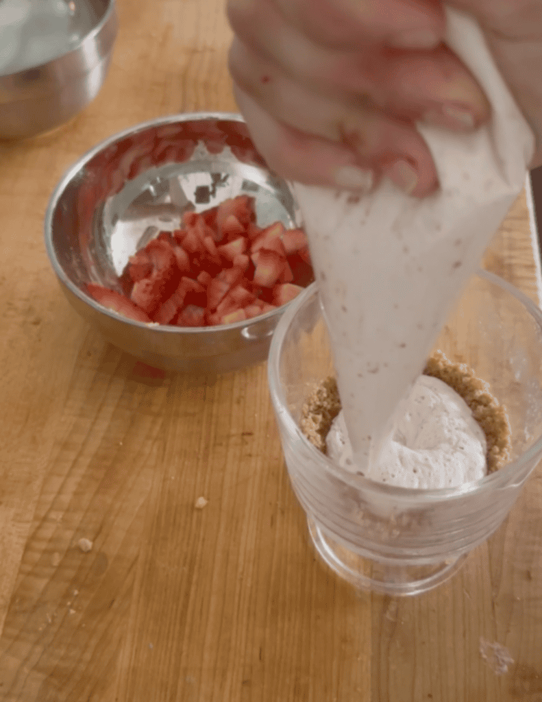 Pouring strawberry ice cream into a glass over homemade pizzelle cookies.