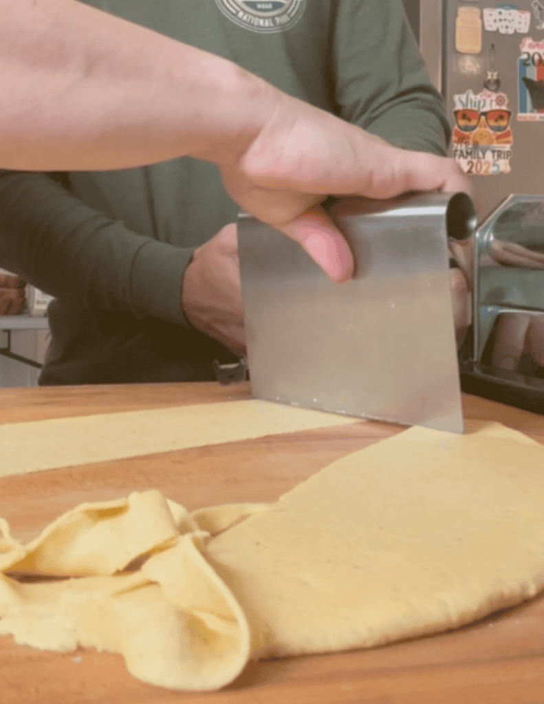 Using a dough cutter to cut through wonton wrappers