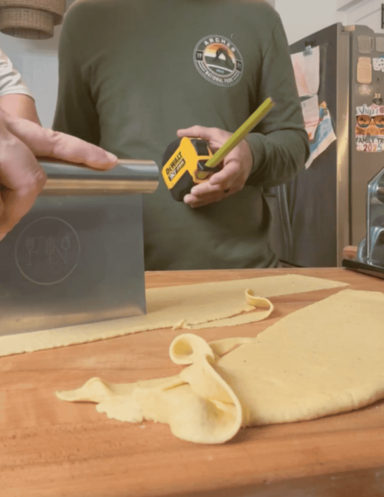 Gluten free wonton wrapper being cut with a dough scraper to 3 inches in size.