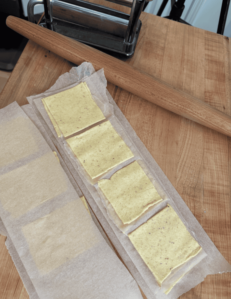 Gluten free wonton wrapper with 3 inch squares lined on parchment paper, 4 per row.