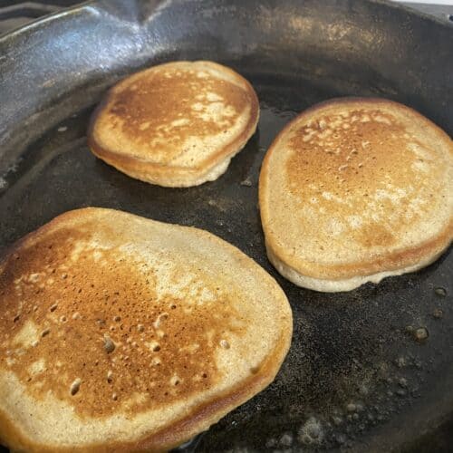 three pancakes baking in cast iron