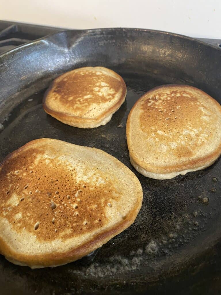 three pancakes baking in cast iron