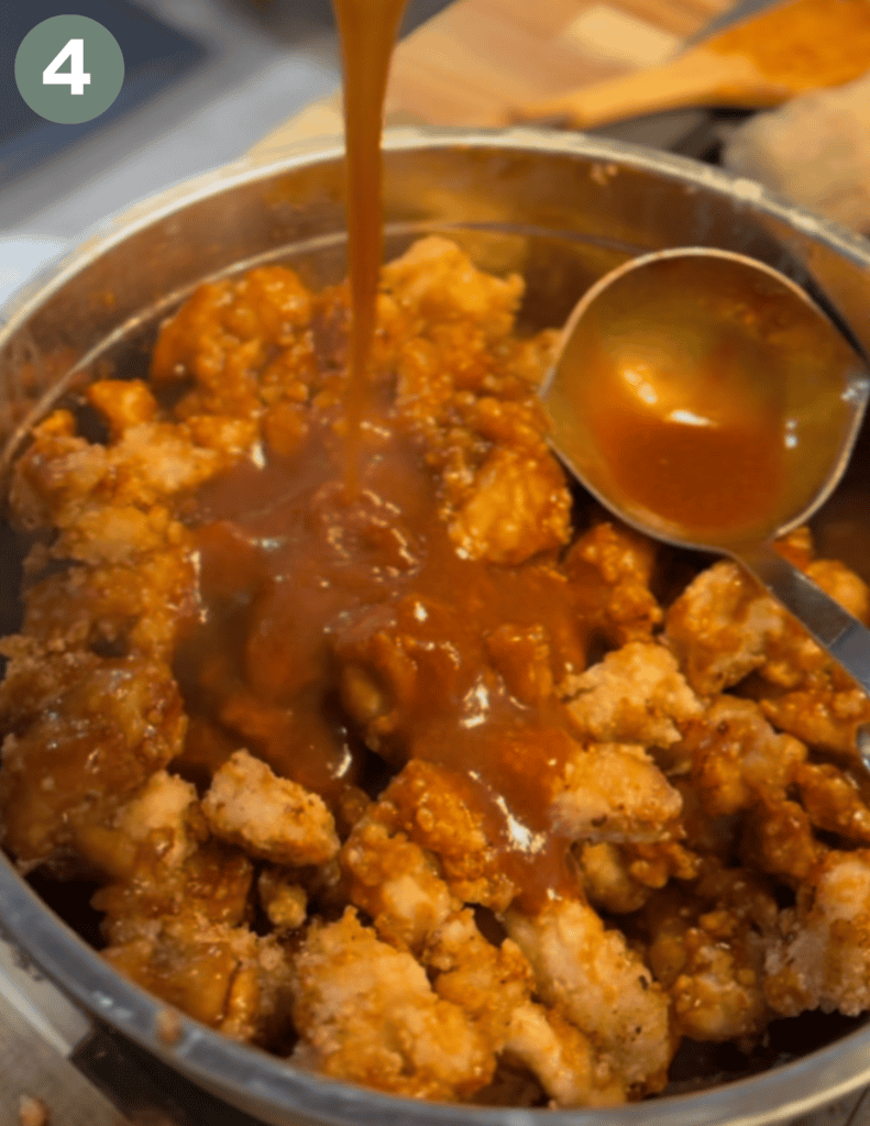 Metal ladle scoop in a bowl of chicken chunks and sauce pouring on top 
