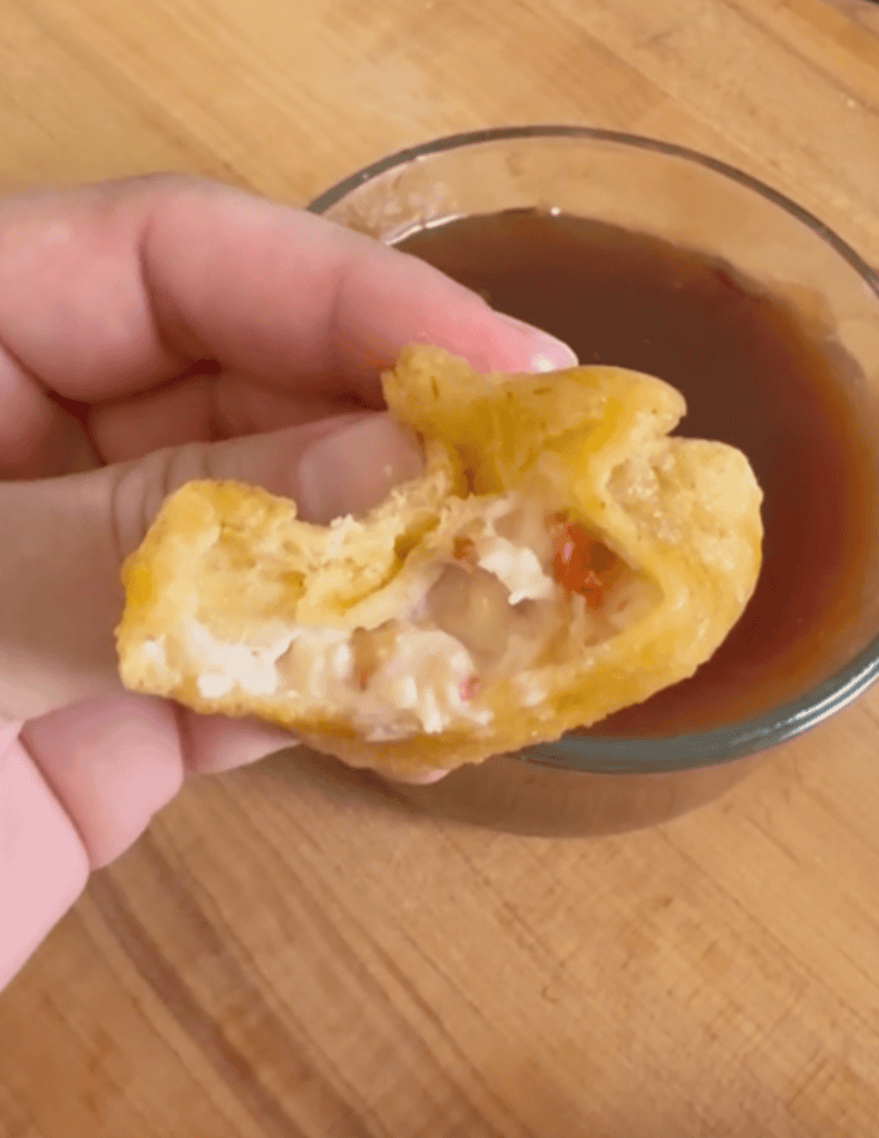 gluten free crab rangoon with a bite taken out of it exposing the inside.