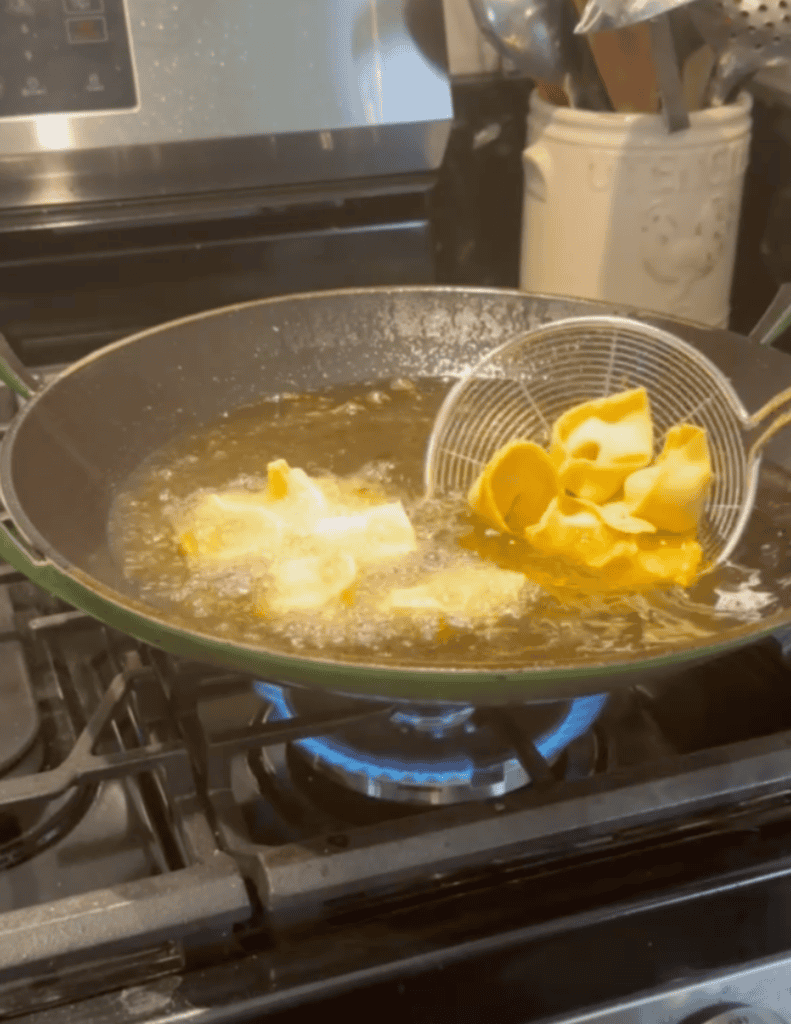 frying wontons in the oil in the wok.
