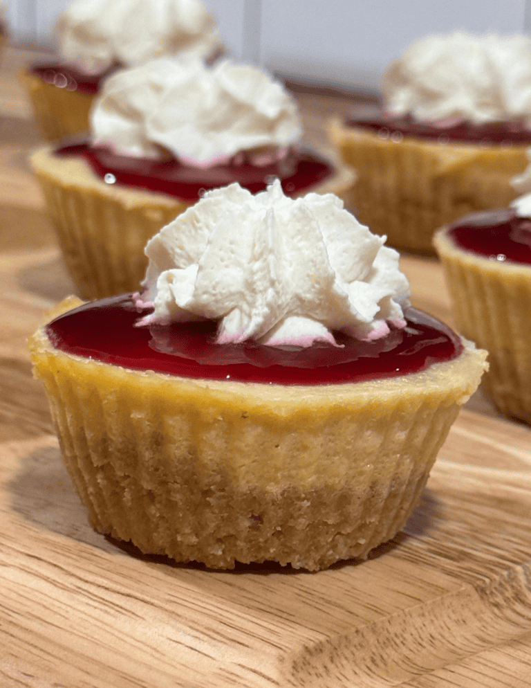 gluten free raspberry cheesecake bites with raspberry compote on top and whipped cream