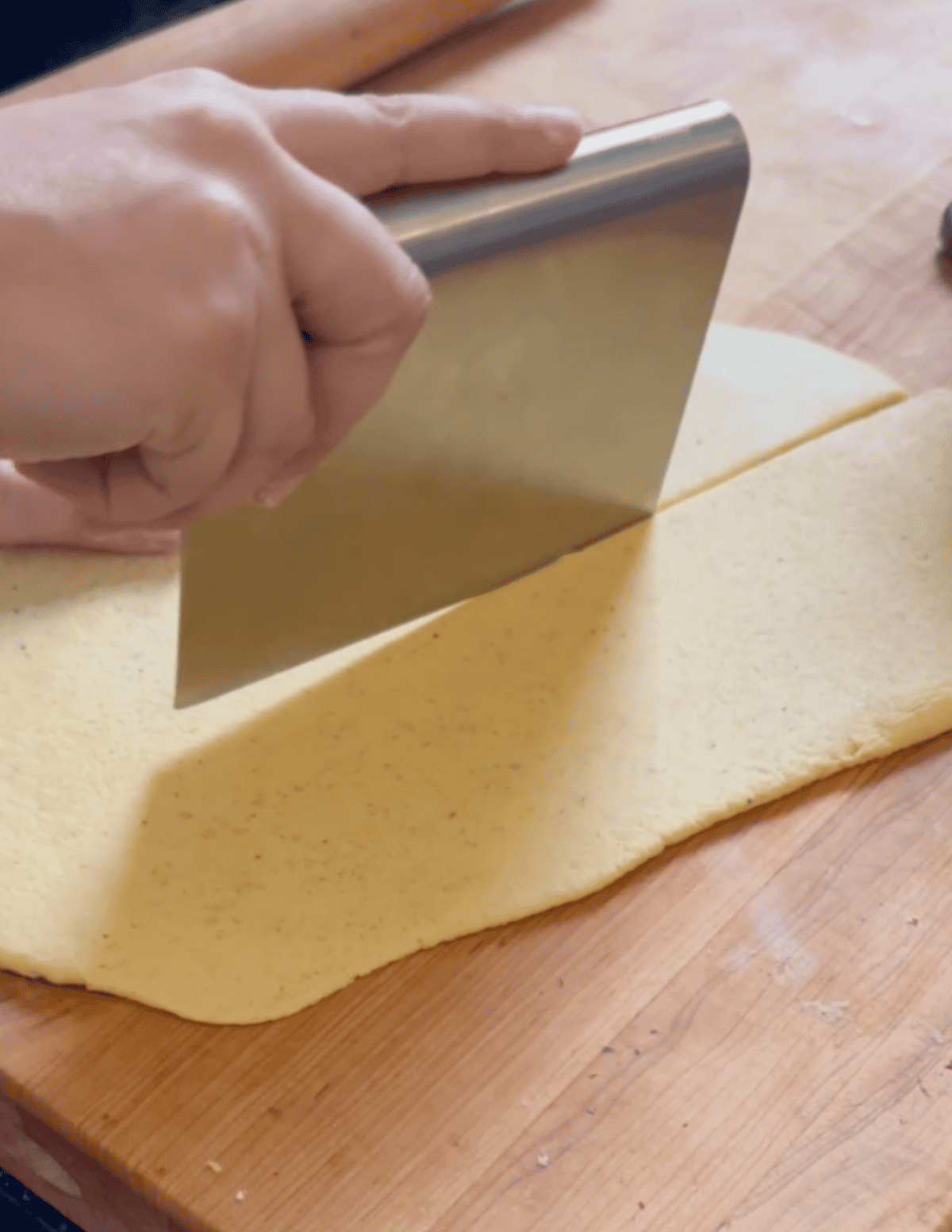 cutting wonton dough in half with dough scraper