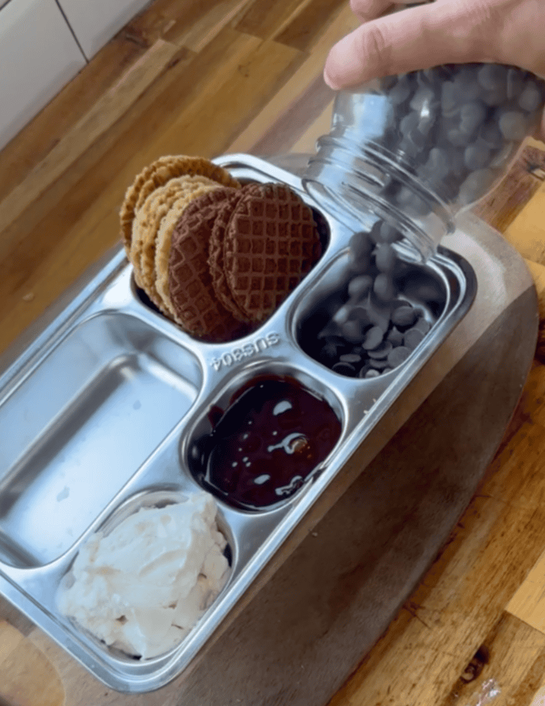 Ice cream nachos with cookies, chocolate, and berries on a metal tray.