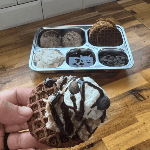 Gluten-free ice cream nachos with chocolate drizzle and cookies on a waffle cone.