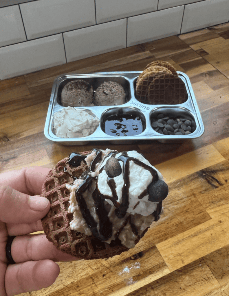 Gluten-free ice cream nachos with chocolate drizzle and cookies on a waffle cone.