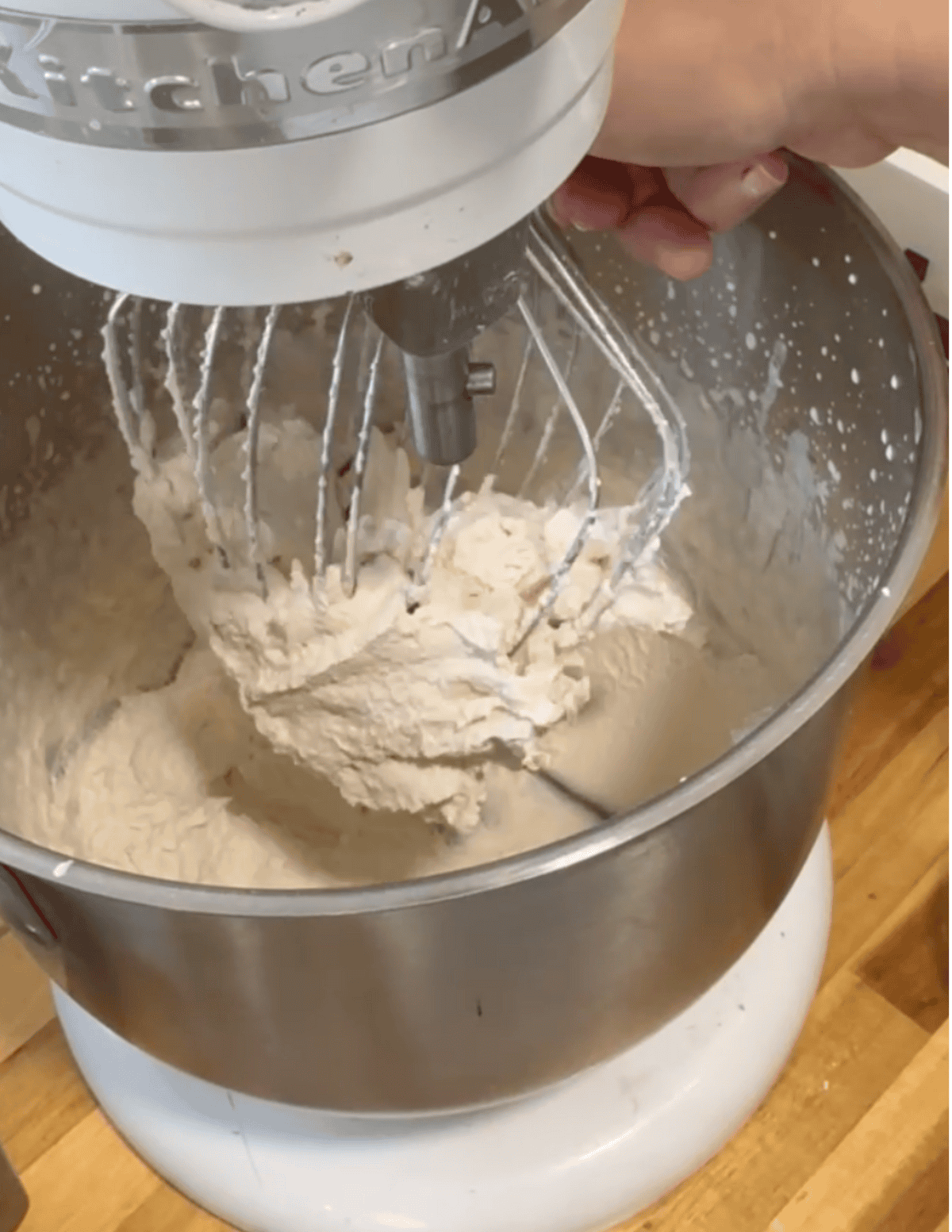 Mixer blending dough with flour and ingredients.