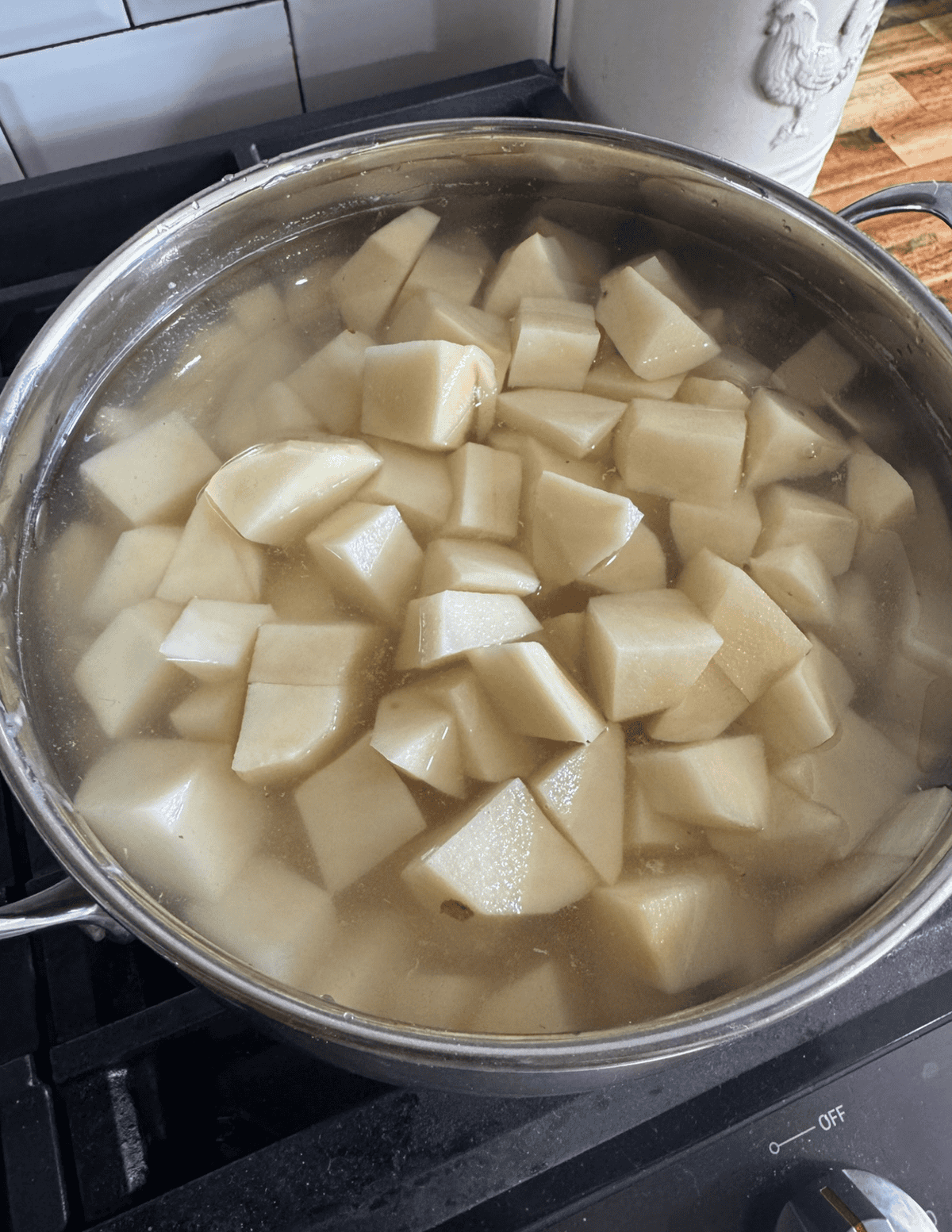 Potato soup cooking in a pot with diced potatoes boiling on the stove.
