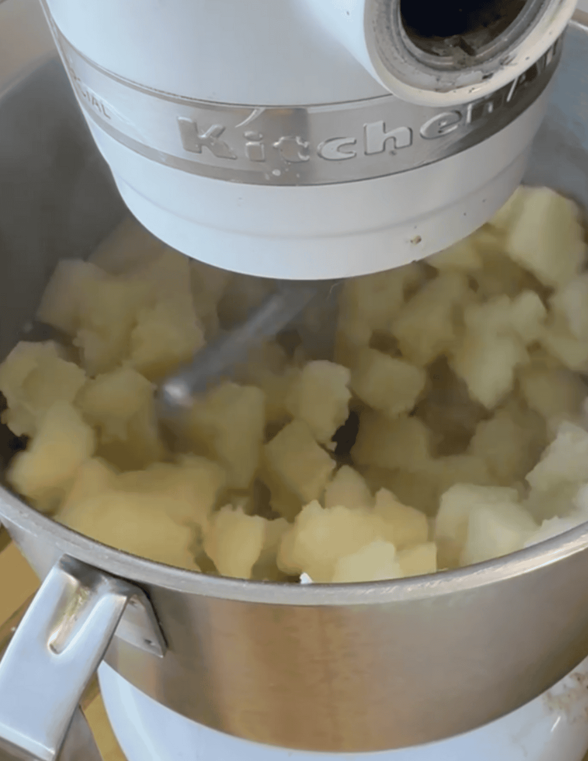 Close-up of mashed potatoes being prepared with a KitchenAid mixer.
