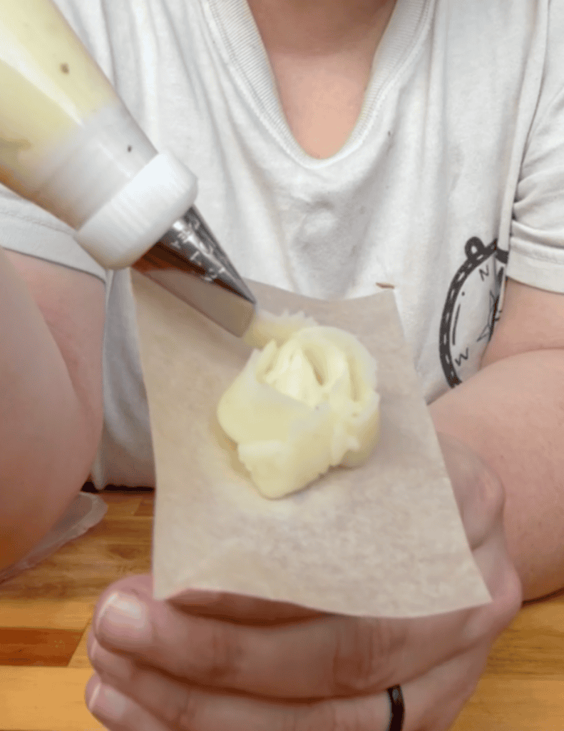 Person piping mashed potatoes onto parchment paper for farm-fresh family meal.