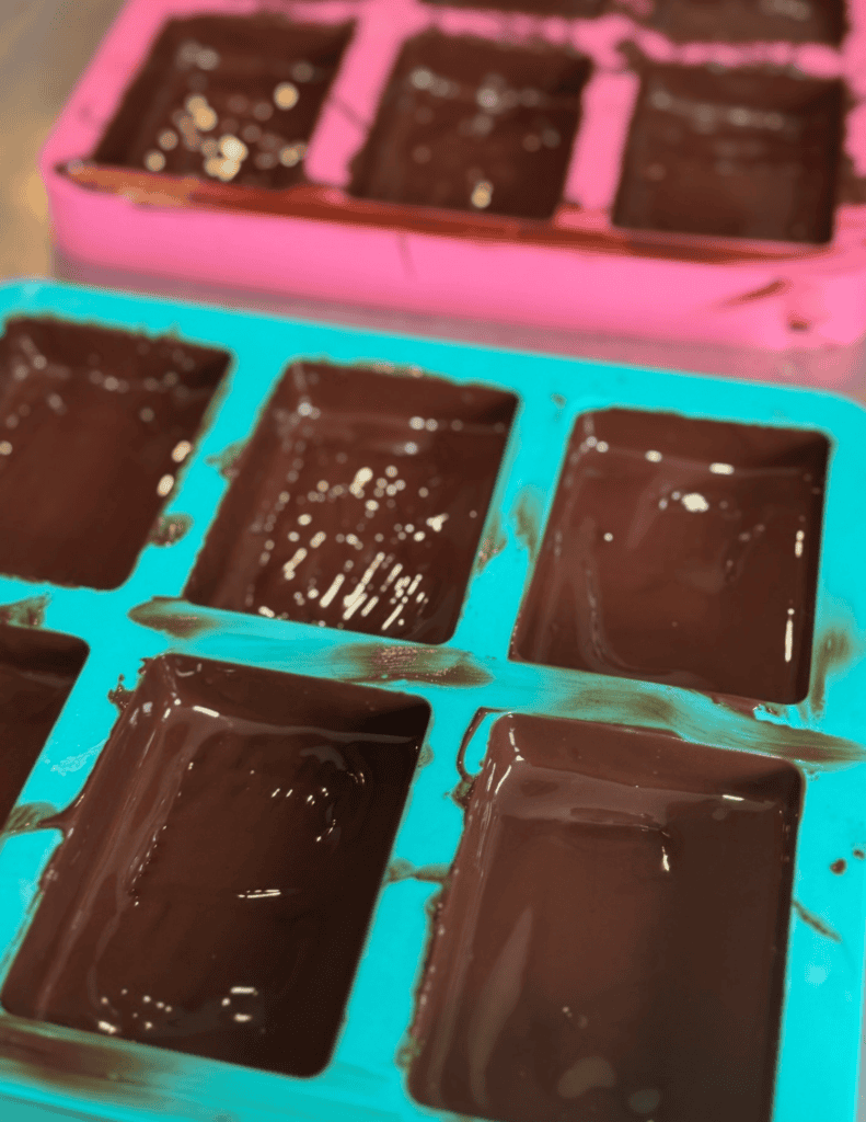 Delicious homemade chocolate fudge poured into colorful ice cube trays for easy portioning and stora.