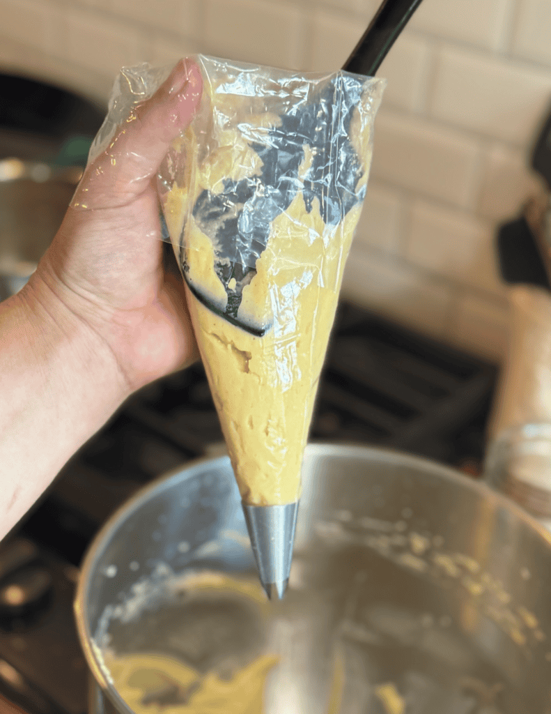 Pastry piping bag filled with yellow batter, ready for baking or decorating.