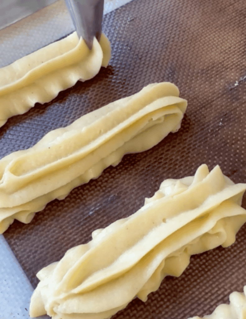 Fresh homemade pastry dough being shaped on a baking sheet.