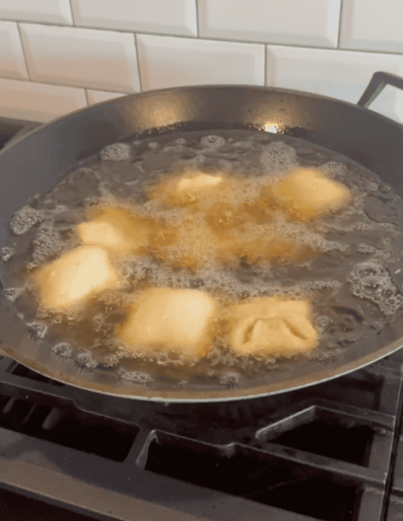 Dumplings frying in a skillet with bubbling oil, showcasing fresh homemade ingredients.