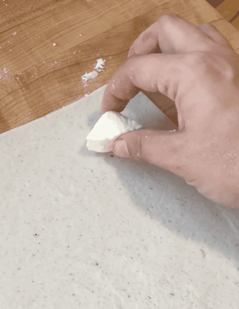 Hand pressing dough on a floured surface for baking.