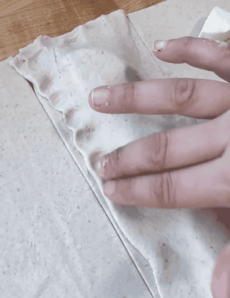 Hand pressing homemade flatbread dough on parchment paper.