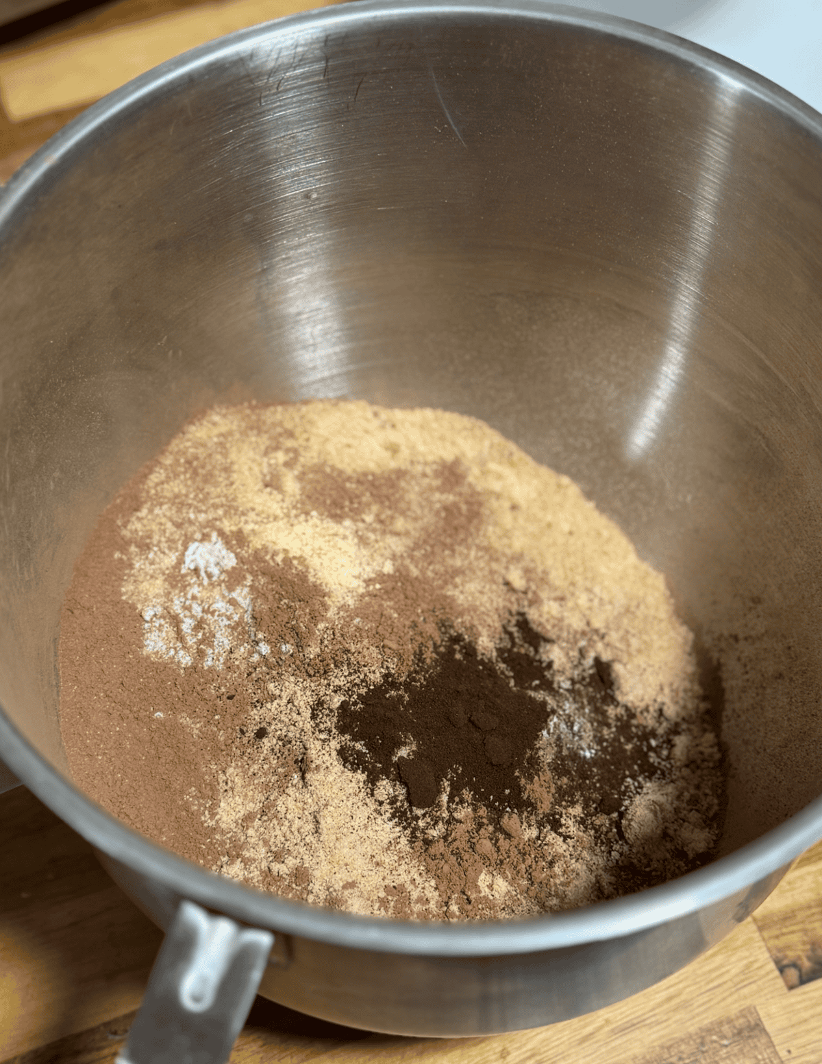 Chocolate cake mix ingredients in a metal mixing bowl for baking.