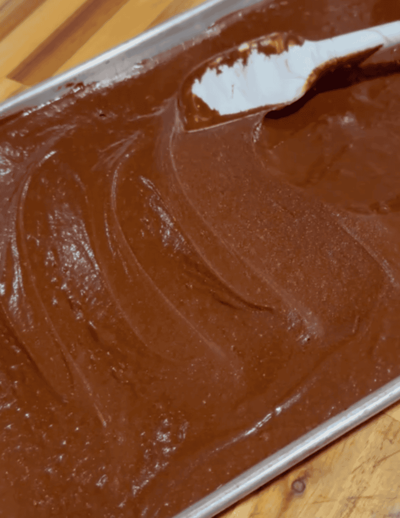 Chocolate fudge in a metal tray with a spatula.