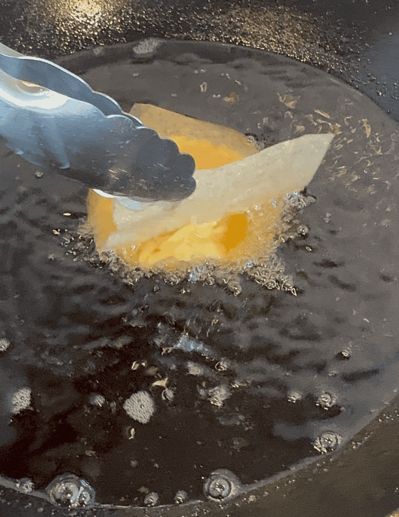 Cooking fresh farm eggs in a pan with tongs.