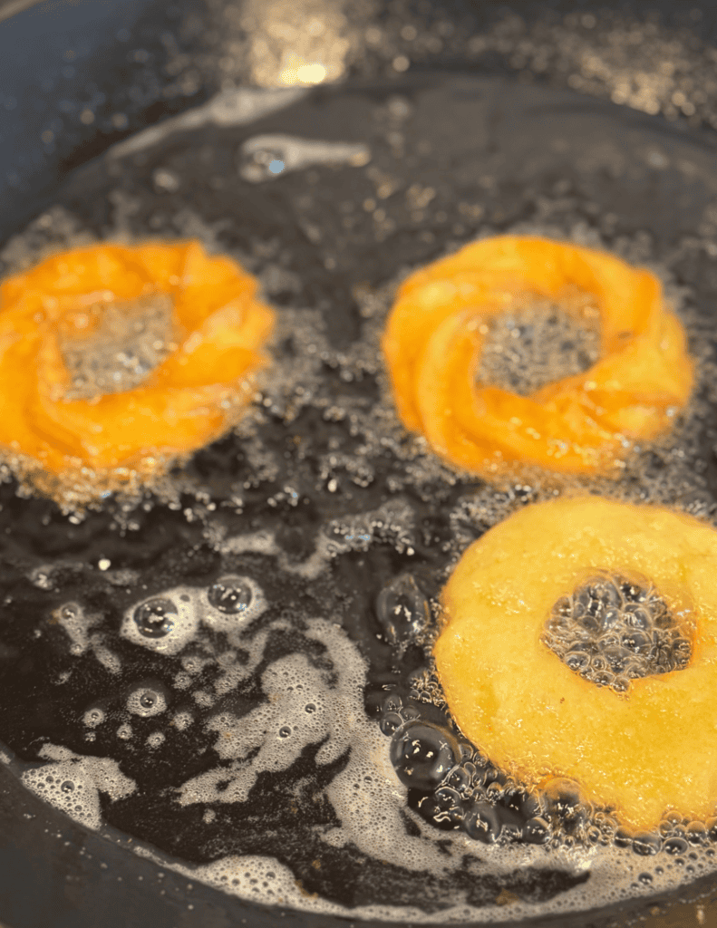 Crispy onion rings frying in hot oil, golden and delicious.