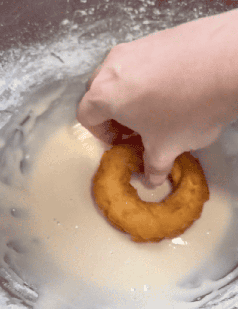 Onion ring being dipped in batter for fresh, crispy homemade onion rings.