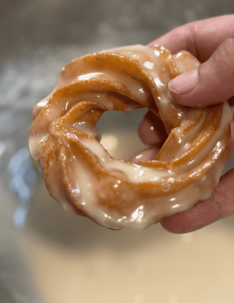Donut with caramel glaze held in hand, showcasing fresh, homemade bakery treats.