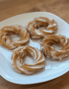 Fresh glazed donuts on a white plate, ready to enjoy.