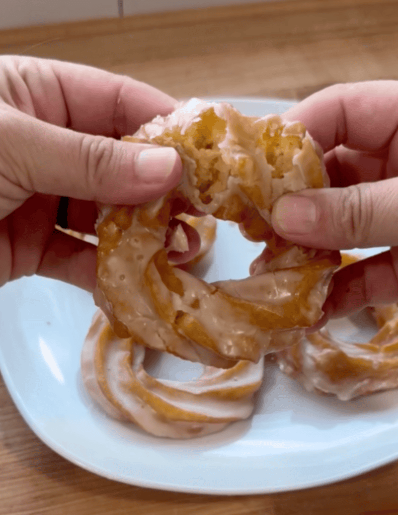 Delicious homemade glazed donuts being held, showcasing their soft interior and sweet glaze.