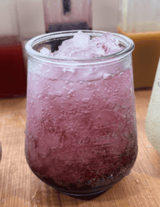 Bright pink berry lemonade served over ice in a clear glass.
