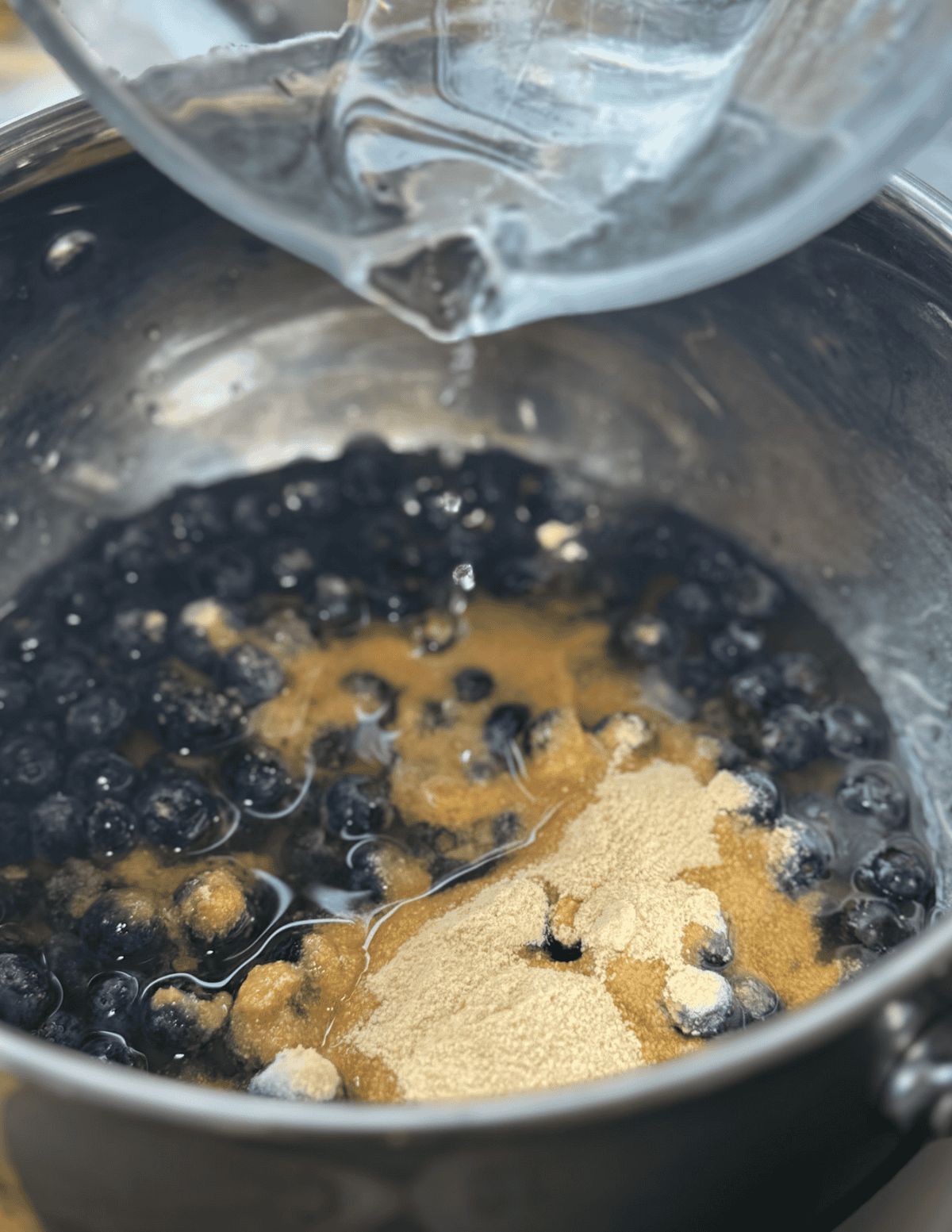 Blueberries and sugar boiling in a pot for homemade jam.